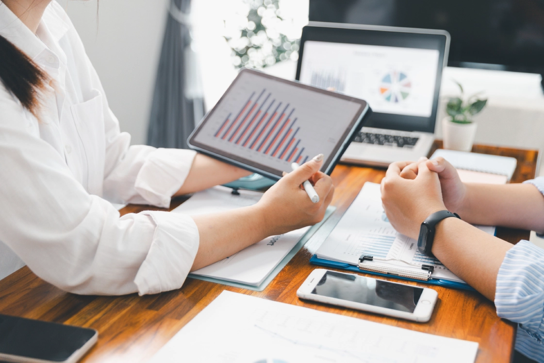 Business meeting with tablet displaying graphs.